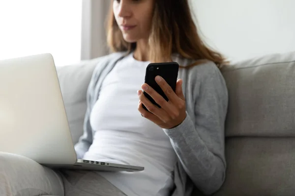 Young woman sit on couch busy using devices — Stock Photo, Image