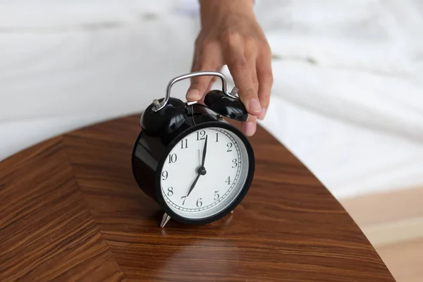 Female turn off wind-up alarm clock at home