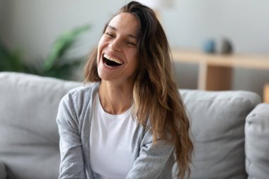 Mutlu genç bir kadın kanepede oturup biriyle konuşuyor.