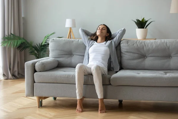 Glückliche junge Frau ruht sich auf gemütlichem Sofa aus und atmet frische Luft — Stockfoto