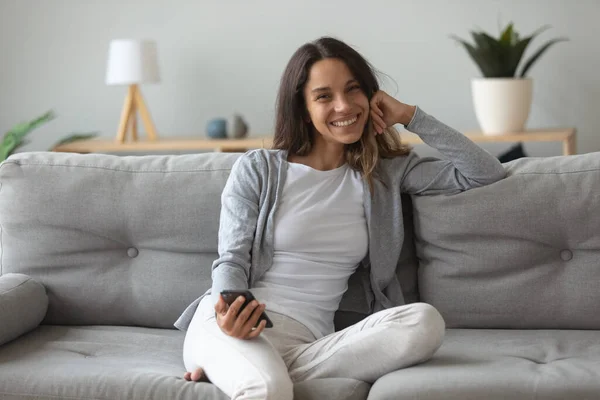 Portrait of happy woman sit on couch with cellphone — Stock Photo, Image