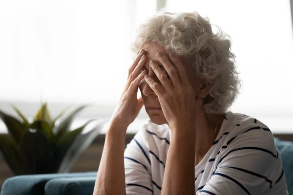 Sconvolta vecchia donna soffre di mal di testa a casa — Foto Stock