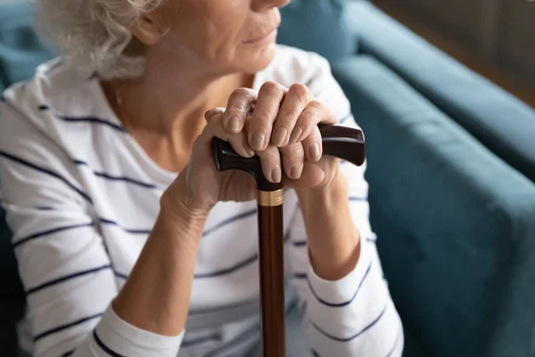 Mujer vieja trastornada con caña de luto pensando en casa — Foto de Stock