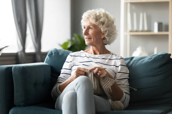 Pensive mature woman relax in living room knitting — Stock Photo, Image