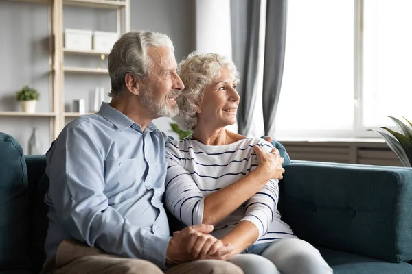 Smiling old couple hug look in distance dreaming — Stock Photo, Image