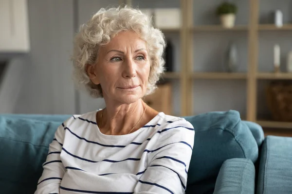Pensive mature woman look in distance feeling lonely