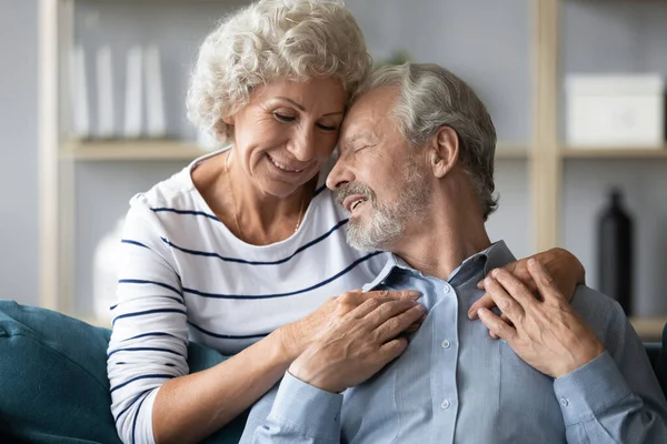 Felice maturo marito e moglie abbraccio a casa divano — Foto Stock