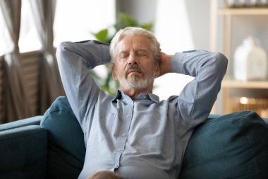 60 'ların barışçıl ihtiyarı oturma odasındaki kanepede dinleniyor.