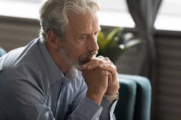 Unhappy elderly man look in distance thinking of past