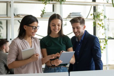 Çok ırklı iş arkadaşları ofiste tablet kullanarak fikirleri tartışıyor