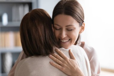 Orta yaşlı esmer anneyi kucaklayan şefkatli bir genç kadın..