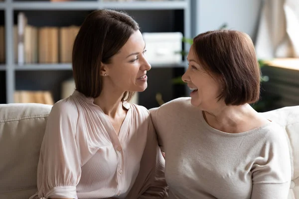 微笑的年轻女子与年老的母亲分享生活的新闻. — 图库照片