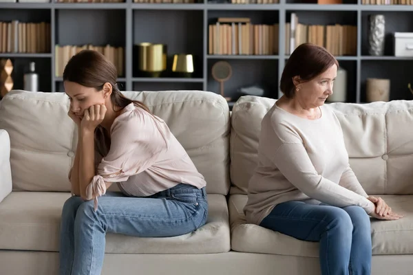 Gestrest jong vrouw zitten afzonderlijk met beledigd volwassen moeder. — Stockfoto