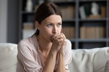 Stresli genç kadın koltukta oturuyor, sorunlar için endişeleniyor..