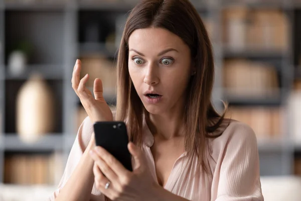 Cerca de la joven sorprendida mujer mirando a la pantalla del teléfono móvil . — Foto de Stock