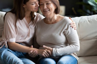 Mutlu orta yaşlı anneyi kucaklayan sevgi dolu genç bir kadın..