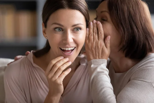 Feliz madre de mediana edad susurrando chismes a la hija adulta . —  Fotos de Stock