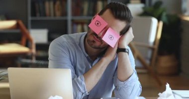Funny worker napping at workplace covering eyes with sticky notes