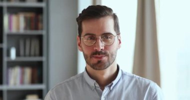 Smiling handsome young businessman wearing glasses looking at camera