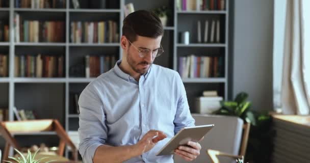 Jeune homme d'affaires utilisant une tablette numérique debout dans le bureau — Video