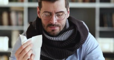 Unhealthy ill man blowing running nose drinking hot tea