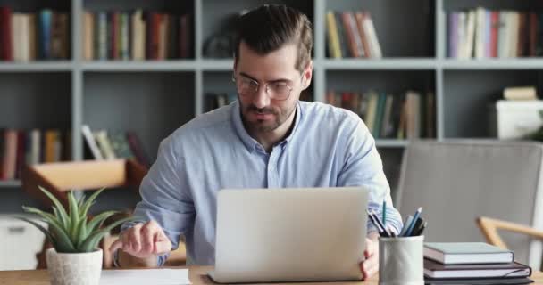 Uomo d'affari concentrato che digita sul computer portatile seduto alla scrivania dell'ufficio — Video Stock