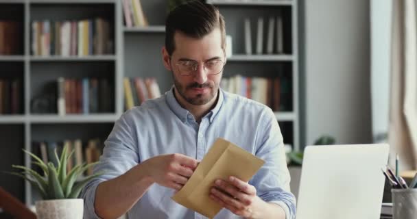 Захоплений підприємець чоловічої статі відкриває листа на пошту, читаючи хороші новини — стокове відео