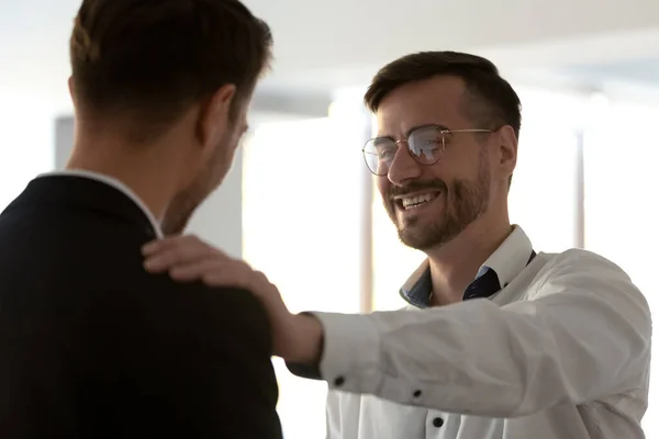 Glimlachende mannelijke teamleider legt hand op collega 's schouder. — Stockfoto