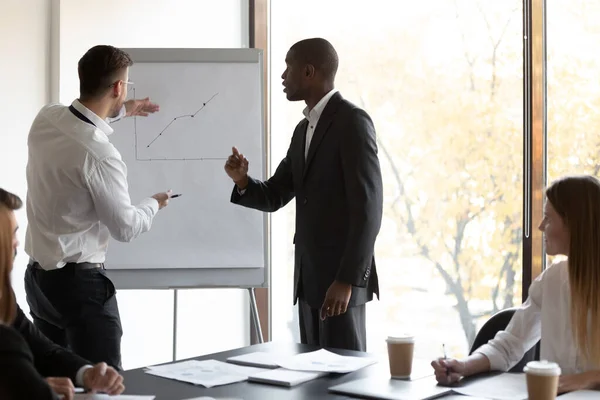 Two confident multiracial male employees presenting financial project positive results. — Stock Photo, Image