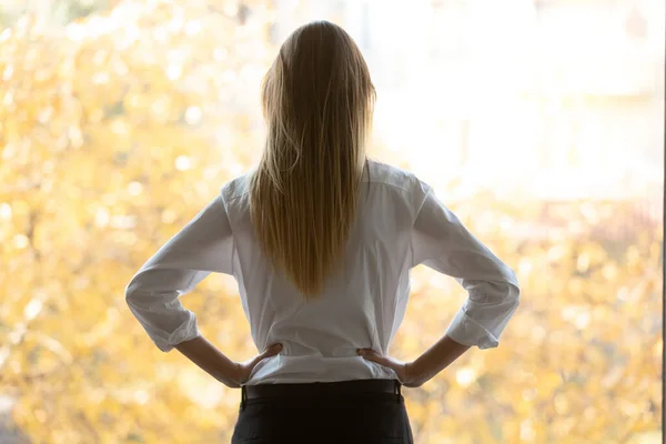 Vista trasera reflexiva mujer de negocios milenaria mirando a la ventana de la oficina . —  Fotos de Stock