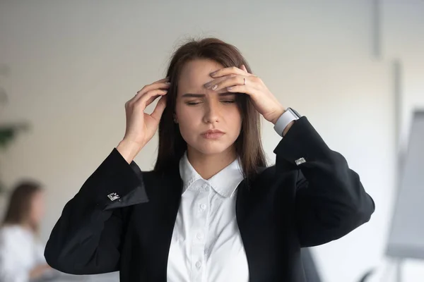 Gestresste Büroangestellte leidet unter plötzlichen Kopfschmerzen. — Stockfoto