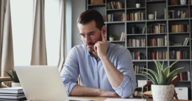 Concentrated businessman thinking of problem solution working on laptop