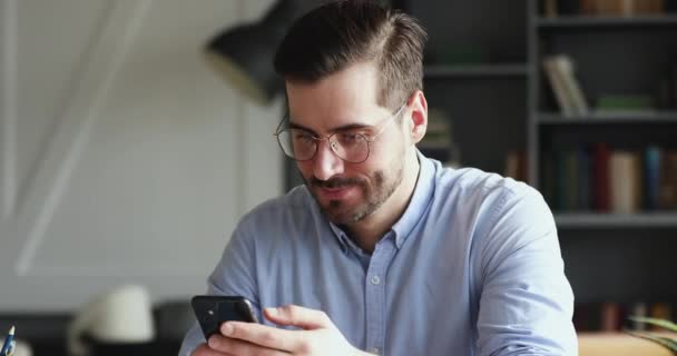 Smiling young man using smartphone digital applications indoors — Stok video