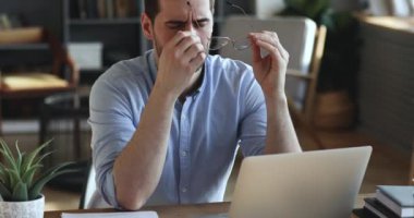 Exhausted businessman taking off glasses massaging dry irritated eyes