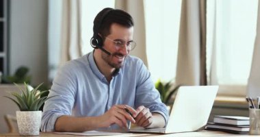 Smiling businessman wear headset making conference video call on laptop
