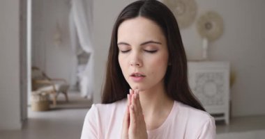 Young woman praying with hope holding hands clasped together