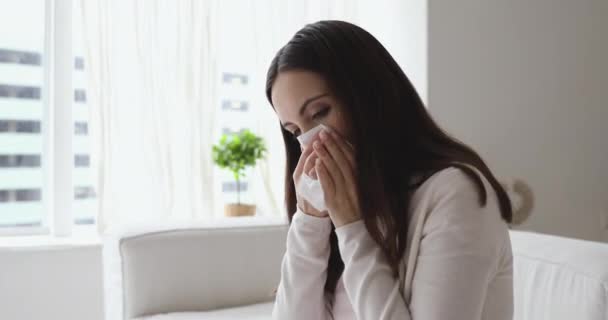 Unhealthy young woman having allergic rhinitis blowing nose at home — ストック動画