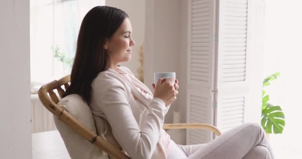 Serene woman drinking warm tea breathing fresh air at home — Stock Video