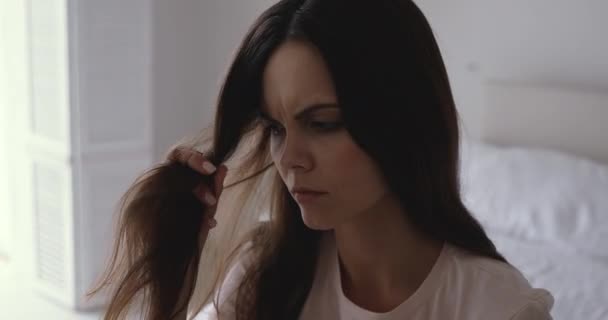 Worried young woman holding brittle hair looking damaged and dry — Stock Video