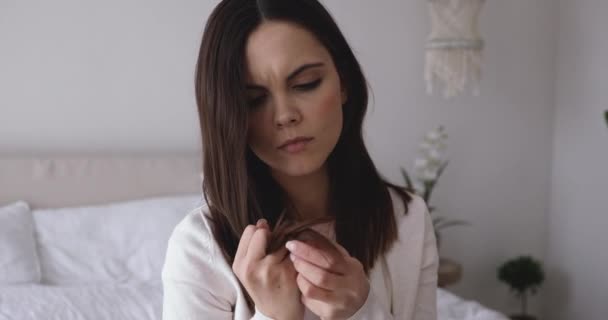 Расстроенная молодая женщина чувствует разочарование из-за секущихся кончиков волос — стоковое видео