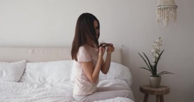 Depressed girl sitting on bed upset about brittle damaged hair