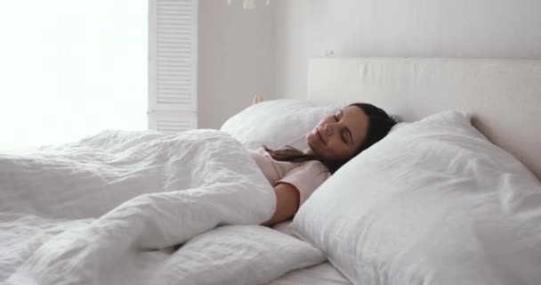 Happy young woman stretching waking up in comfortable bed — Stok video