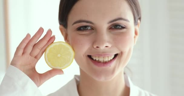 Smiling pretty young woman holding lemon looking at camera — Stockvideo