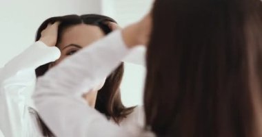 Happy confident girl looking in mirror enjoying healthy hair