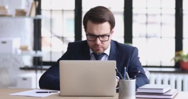 Angry stressed businessman wearing suit feeling mad about broken laptop