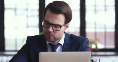 Ciddi düşünceli bir iş adamı dizüstü bilgisayarda çalışıp notlar alırken sorunlar yaşıyor.