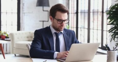 Focused businessman doing research on laptop making notes at work