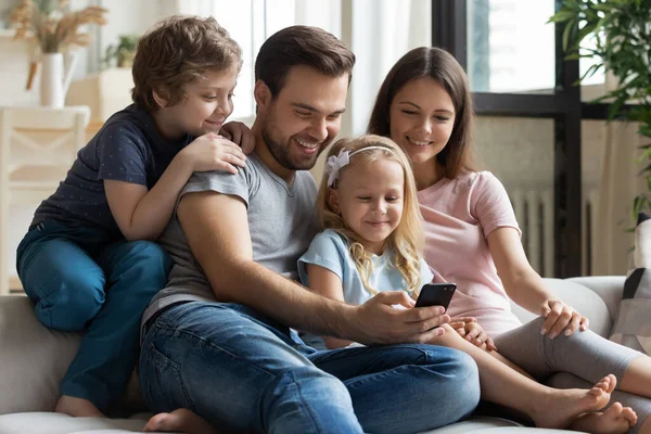 Lycklig familj med barn njuter av video på cellen — Stockfoto