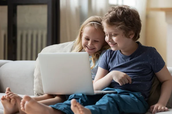 Smarta syskon som använder laptop hemma tillsammans — Stockfoto