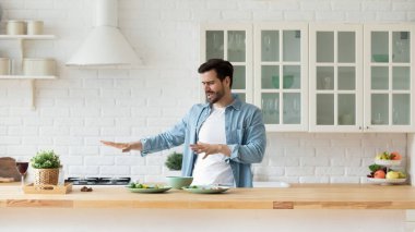 Modern mutfakta dans eden, yemek hazırlayan komik genç adam.